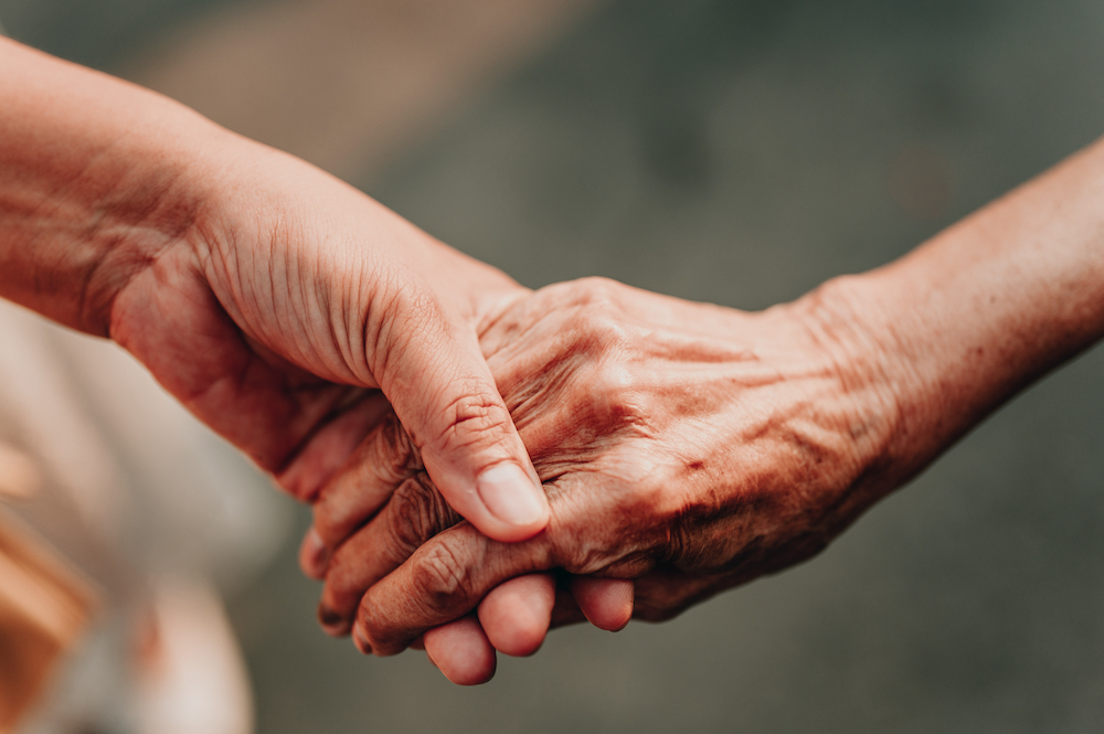 A caregiver holds hands with a senior loved one