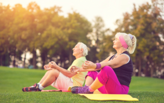 A senior couple sit outside while doing yoga