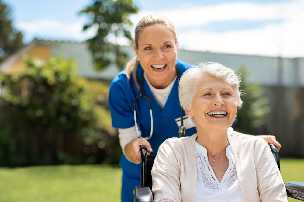 A happy senior woman and her nurse spend time outdoors