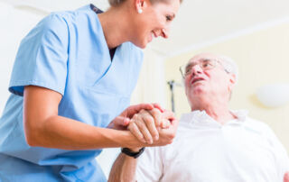 A senior man and his nurse hold hands at respite care