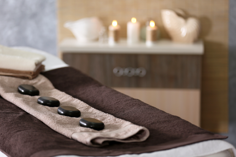 Hot stones lines up on a massage therapy bed