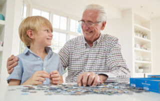 A senior man and a grand son do a puzzle together