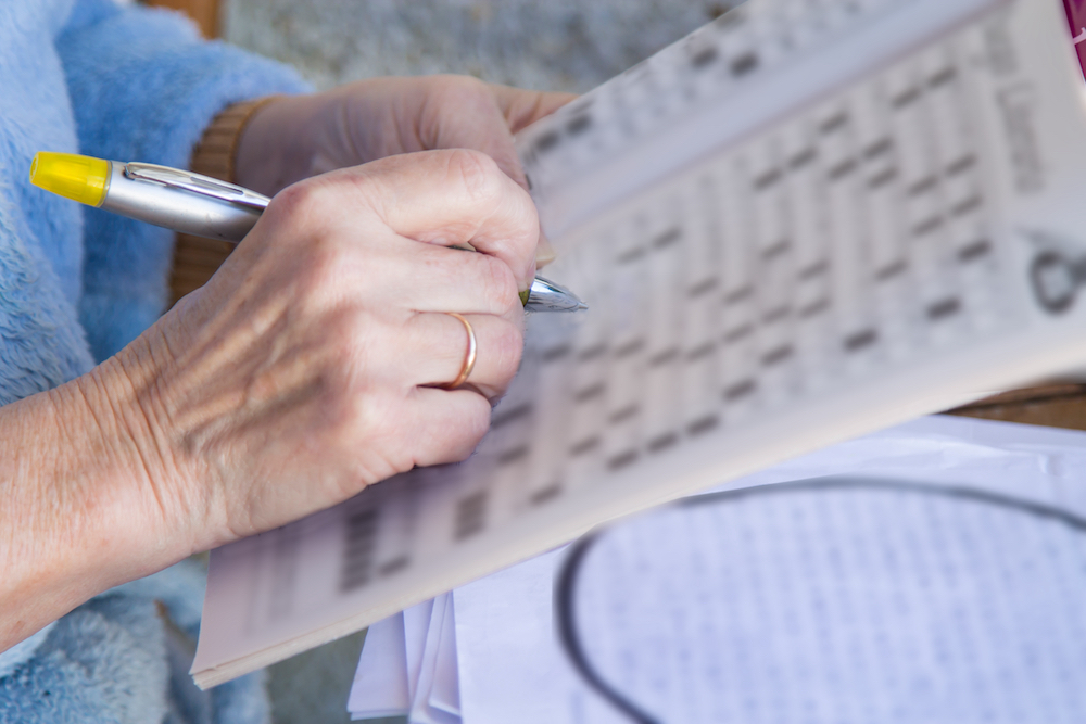 A senior woman does a crossword in the newspaper