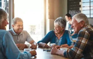 Four senior citizens sitting around a table and smiling.